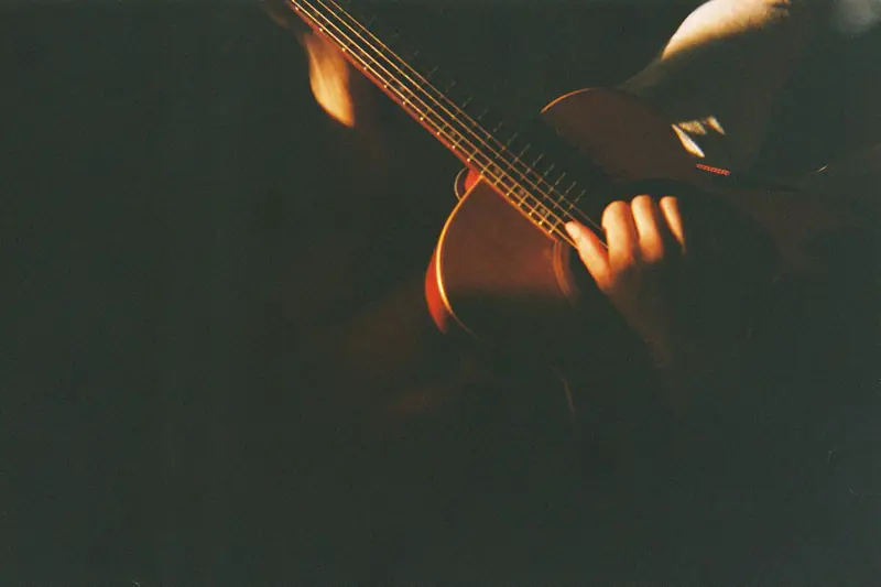 Detalle de manos sobre las cuerdas de una guitarra, en película